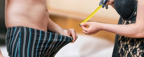 Una mujer mide la longitud de un miembro de un hombre